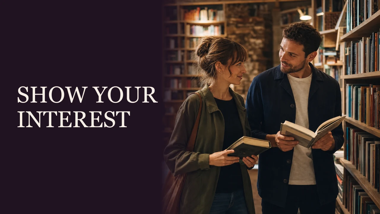 A woman and man sharing subtle eye contact while holding books beside the words Show Your Interest.